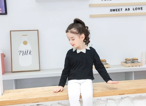Dettaglio maglietta nera a maniche lunghe per bambine con colletto a fiocco in tulle bianco