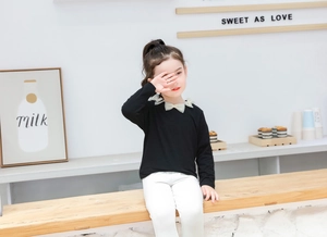Dettaglio maglia nera a maniche lunghe da bambina con delicato fiocco in tulle sul collo