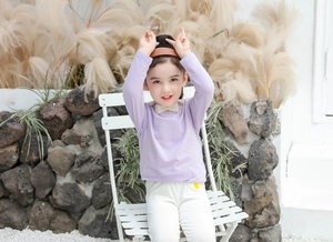 Dettaglio maglia a maniche lunghe lavanda con fiocco color panna per bambina