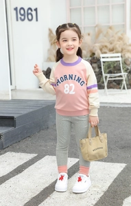 Detail of child's pink color-blocked sweatshirt with MORNING 82 print and cotton texture