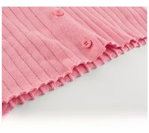 Detailed close-up of pink knit cardigan hem showing vertical texture and resin buttons