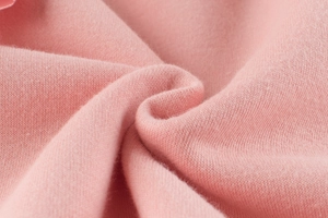 Dettaglio macro che mostra la texture del tessuto di cotone a maglia rosa morbido