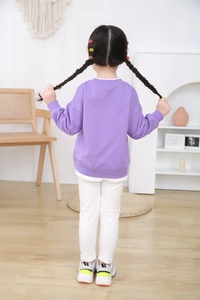 Detail view of girls purple layered sweatshirt with ribbed cuffs and casual white pants