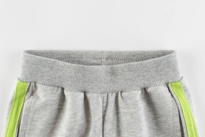 Detail of girls' heather grey joggers featuring ribbed waistband and neon green stripes