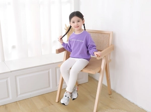 Detailed view of kids' purple sweatshirt with 'humans are born good' print and white pants