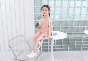Dettaglio della tuta sportiva rosa e bianca da bambina con nastro HAPPY sulle maniche