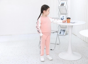 Dettaglio della tuta rosa da bambina con maniche bianche e nastro con scritta HAPPY