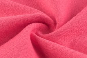Macro shot of watermelon red knitted fabric texture showing soft cotton blend quality