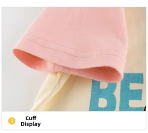 Detailed shot of pink sleeve cuffs and cream cotton fabric with BE letter print