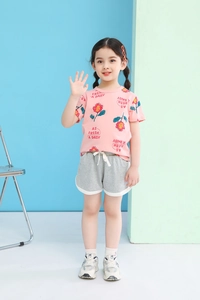 Close-up of girls pink daisy print t-shirt and grey shorts outfit set with white drawstrings