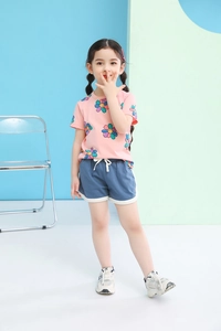 Detail of pink cotton T-shirt with smile flower prints and blue athletic shorts