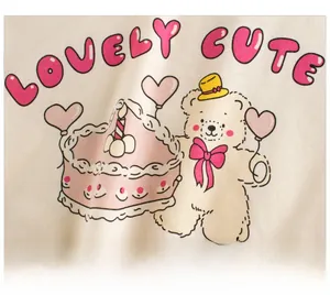 Détail de la broderie ours et gâteau sur le tissu en coton beige du t-shirt enfant