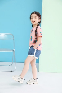 Detail of a pink cotton floral t-shirt and blue drawstring shorts on a child model