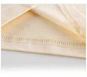 Gros plan de l'ourlet à double couture et de la texture coton sur un t-shirt beige enfant