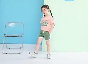 Detail of pink cotton T-shirt with bear print and green elastic drawstring shorts