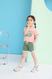 Close-up of pink cotton t-shirt with green cartoon bear print and matching shorts