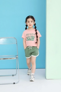 Close-up of girls pink cotton T-shirt with dancing bears and green sports shorts