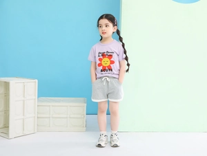 Detail of girls summer outfit featuring a sunflower purple t-shirt and grey sports shorts