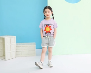 Detail view of girl's purple cartoon t-shirt and grey sports shorts casual summer outfit