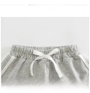 Dettaglio degli shorts grigi in cotone con vita elastica, coulisse bianca e strisce laterali
