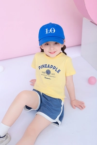 Close-up of kids summer outfit with pineapple graphic tee, navy shorts and blue cap