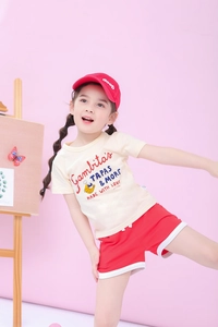 Detailed view of kids summer set with beige t-shirt, red shorts and baseball cap