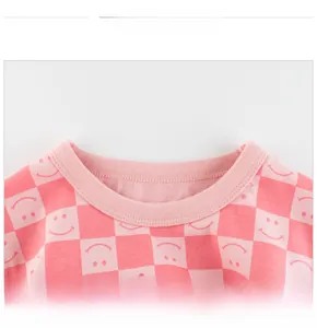 Close-up of pink checkered kids cotton T-shirt showing round neckline and sewing detail