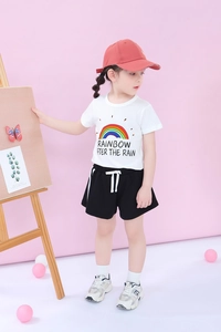 Girl's summer outfit detail with rainbow t-shirt and black shorts in a studio setting