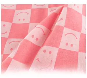 Detail of pink checkerboard knit fabric featuring a simple smiley face print for kids