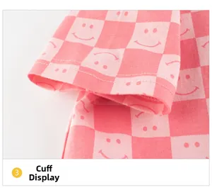 Close-up of pink checkered kids t-shirt showing double-stitch cuff detail and smiley print