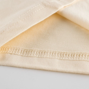 Détail de l'ourlet à double couture et de la finition soignée sur un t-shirt enfant en coton