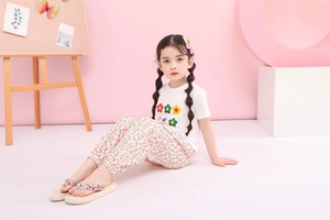 Detail eines weißen Mädchen-T-Shirts mit bunten Blumen und floraler Stoffhose