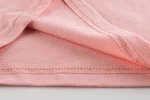 Détail du tissu en maille de coton rose montrant la double couture et les finitions soignées