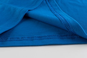Dettaglio dell'orlo della maglietta blu per bambini con doppia cucitura in puro cotone
