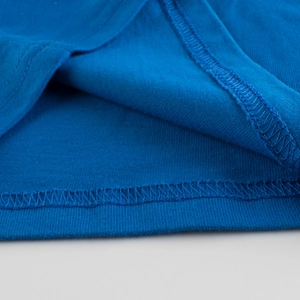 Dettaglio delle cuciture dell'orlo e della trama del tessuto di una t-shirt in cotone blu