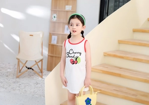 Detail shot of a white sleeveless cherry print dress with red contrast piping for girls
