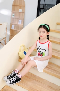 Detail of white cotton girls cherry print dress with red contrast binding and sleeveless cut