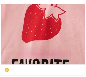 Close-up of pink knit fabric with red strawberry print and text for girls summer dress