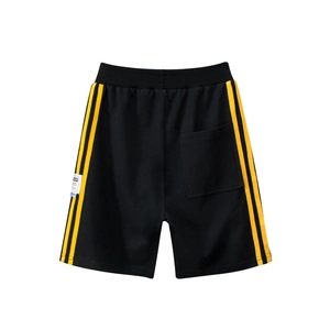 Flat lay of black cotton kids sports shorts featuring bright yellow side stripes