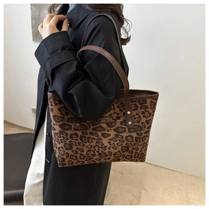 Détail du cabas à imprimé léopard avec brides en cuir marron et logo de marque
