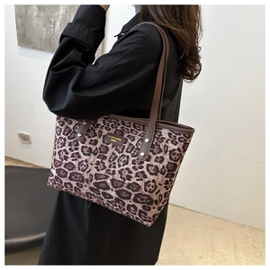 Détail du sac cabas léopard avec poignées en cuir marron et rivets métalliques