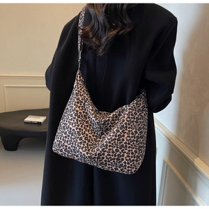 Detail of leopard print tote bag with adjustable shoulder strap on a black coat