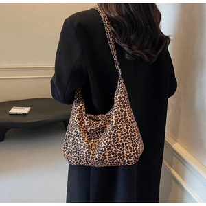 Detailed view of leopard print canvas tote bag styled with a black coat in a chic indoor setting