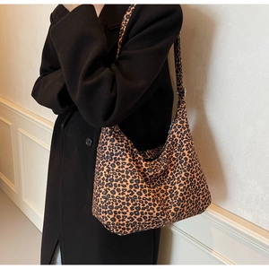 Close-up of leopard print canvas tote bag styled with a black coat and long straps