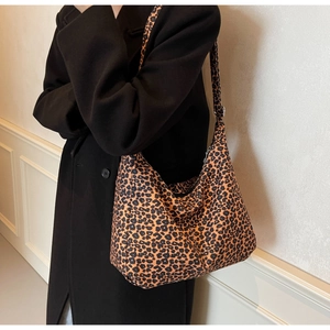 Detail of a large leopard print hobo bag worn over the shoulder on a white background