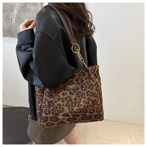 Close-up of leopard print tote bag with brown leather straps and gold metal chain link