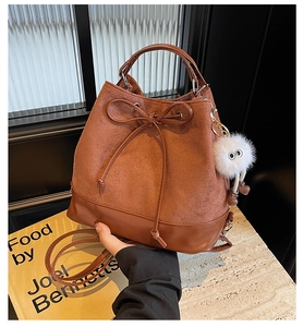 Detail of brown bucket backpack with suede stitching and cute plush doll pendant