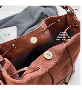 Detail of suede bucket bag featuring strong magnetic snap and drawstring closure