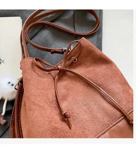 Detail of brown suede bucket bag with drawstring bow and plush eyeball pendant