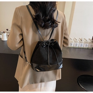 Detailed back view of a black bucket backpack with drawstring and mixed leather textures